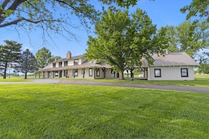 A large, single-story building with a covered porch and a separate white building attached to it. - Landing(43M0)- Sleeps 20 + Airway Strip + Hot Tub (Pleasant Hill)