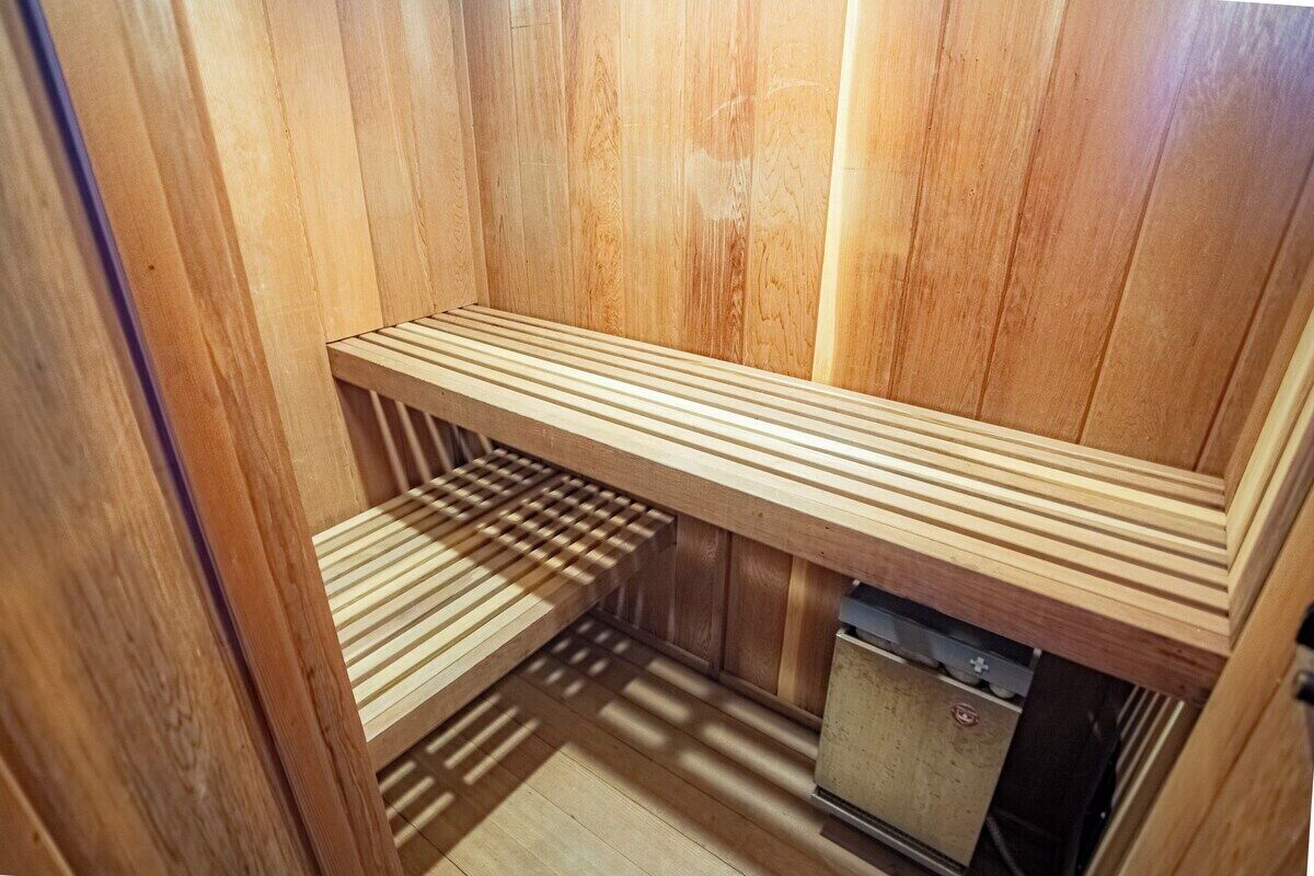 A sauna room with a wooden bench and a small heater.