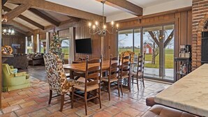A dining area with a wooden table and chairs, a chandelier, and a Christmas tree.