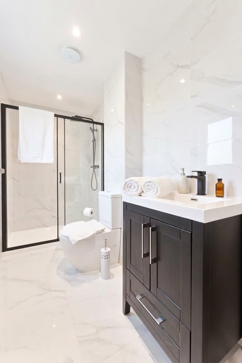 Une salle de bain moderne avec une douche à parois de verre, des toilettes et un meuble-lavabo avec un miroir.