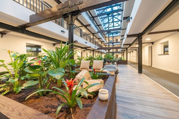 An indoor atrium with a central garden, wooden flooring, and a high ceiling with skylights. - Spacious & Bright 2 Bed Burton-on-Trent Apartment (Burton upon Trent)