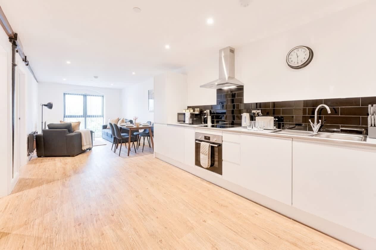A modern kitchen with a central island, a dining area with a table and chairs, and a living room with a sofa and a coffee table.
