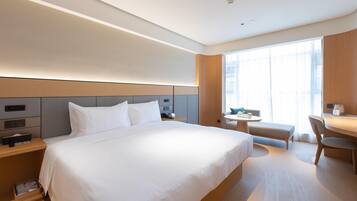 A modern hotel room with a large bed, bedside tables, a desk, and a chair.