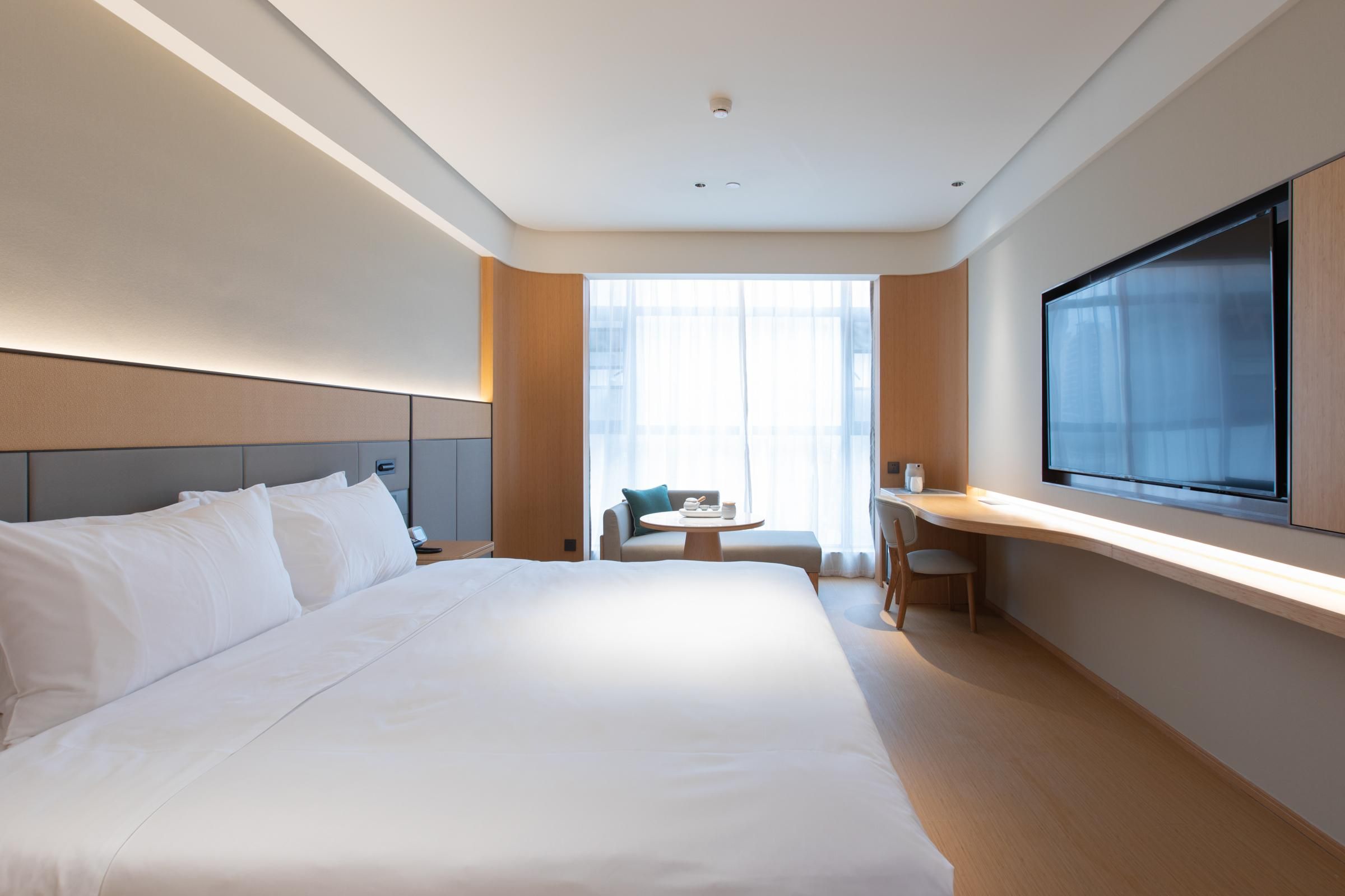 Una habitación de hotel moderna con una cama grande, un escritorio, una silla y una televisión.