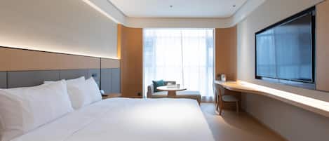A modern hotel room with a large bed, a desk, a chair, and a television.