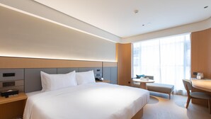 A modern hotel room with a large bed, bedside tables, a desk, and a chair.