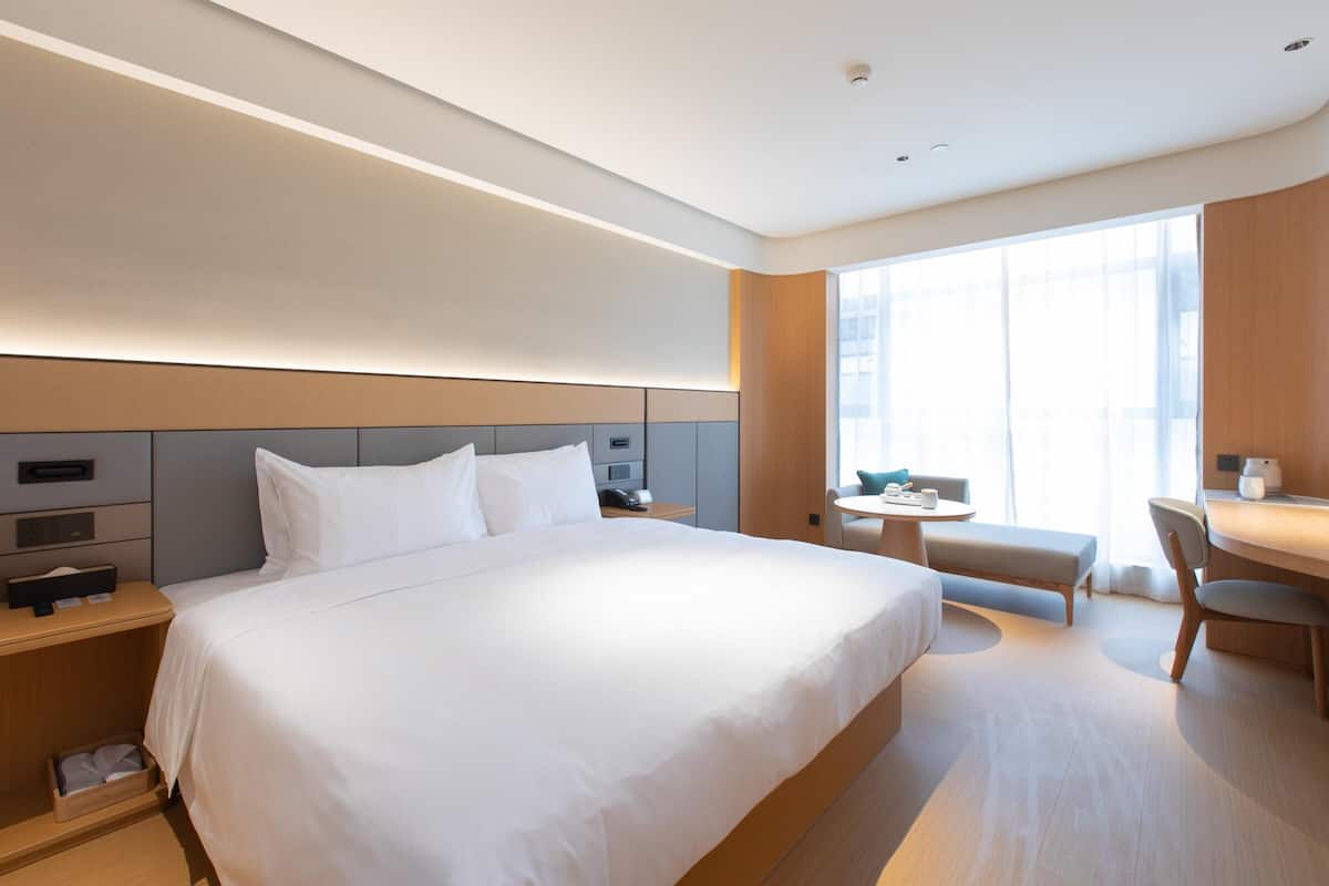A modern hotel room with a large bed, bedside tables, a desk, and a chair.