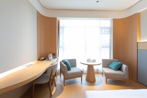 A modern hotel room with a wooden desk, two armchairs, a round table, and a bed. - Ji Hotel Wuhan Hannan Xingcheng Avenue (Wuhan)