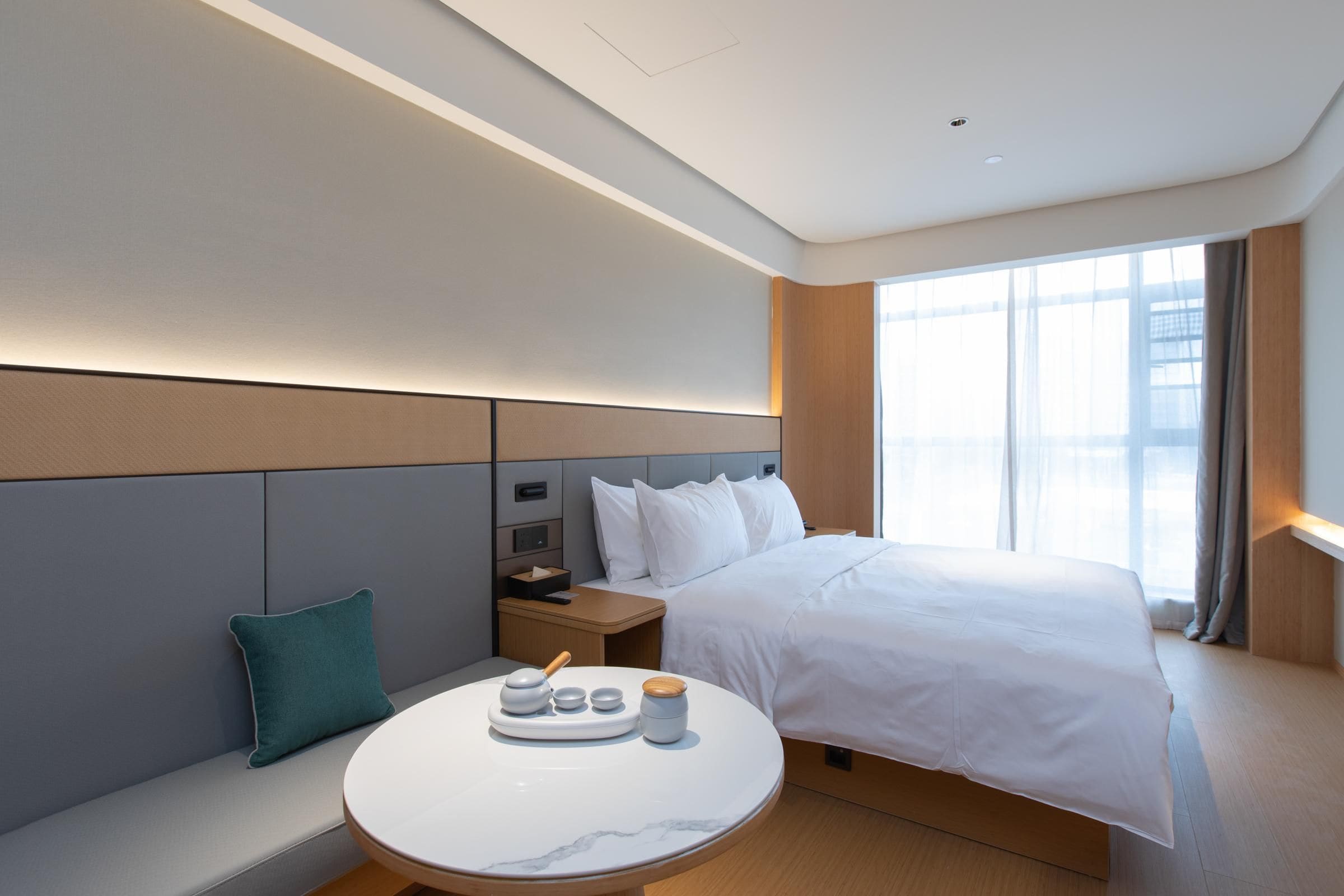 Habitación de hotel con cama, mesita de noche y zona de estar con mesa.