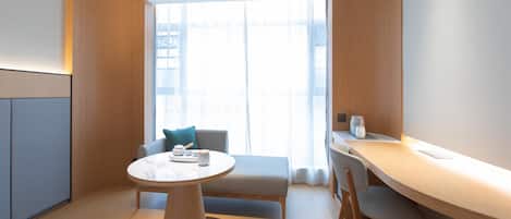 A modern room with a round table, a sofa, and a desk with a chair.