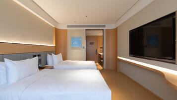 A hotel room with two beds, a TV, and a door leading to a bathroom.