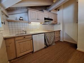 Cozinha compacta com painel de azulejos brancos, armários de madeira e máquina de lavar louça.