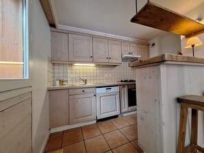 Una cocina con armarios de madera clara, salpicadero de azulejos y una ventana.