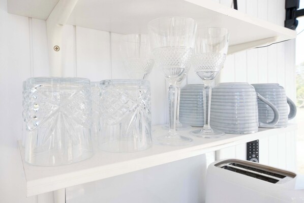 A white shelf with clear glassware and a white toaster.