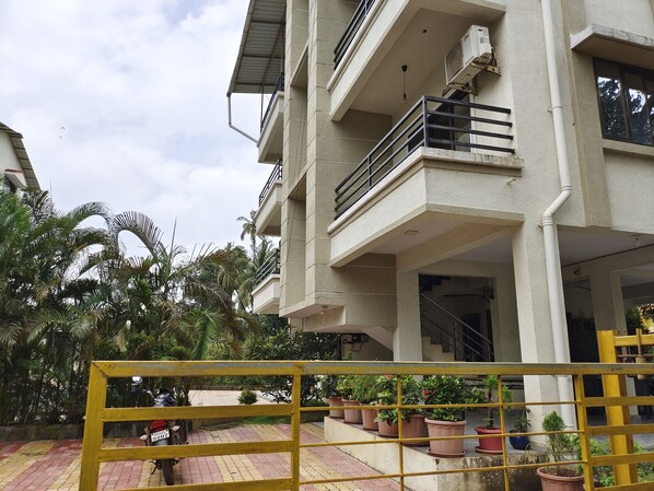 A multi-story building with balconies, a gated entrance, and potted plants. - Anant Villa And Resort (Alibag)