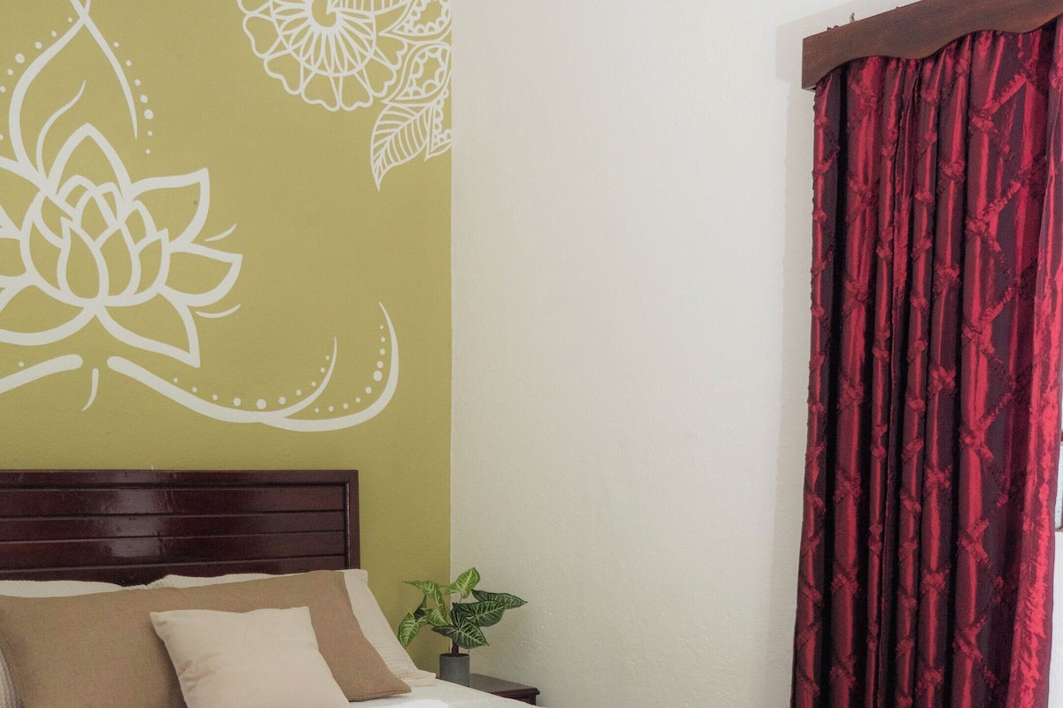 Un dormitorio ordenado con cama, mesita de noche y un banco.