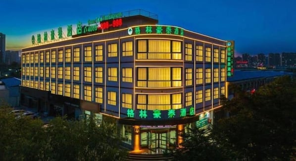 Un hotel de varios pisos con fachada curva, ventanas amplias y señalización que indica las comodidades.