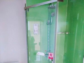 Un espace douche clos par des parois de verre, doté d’un panneau de commande et d’une poignée rouge.