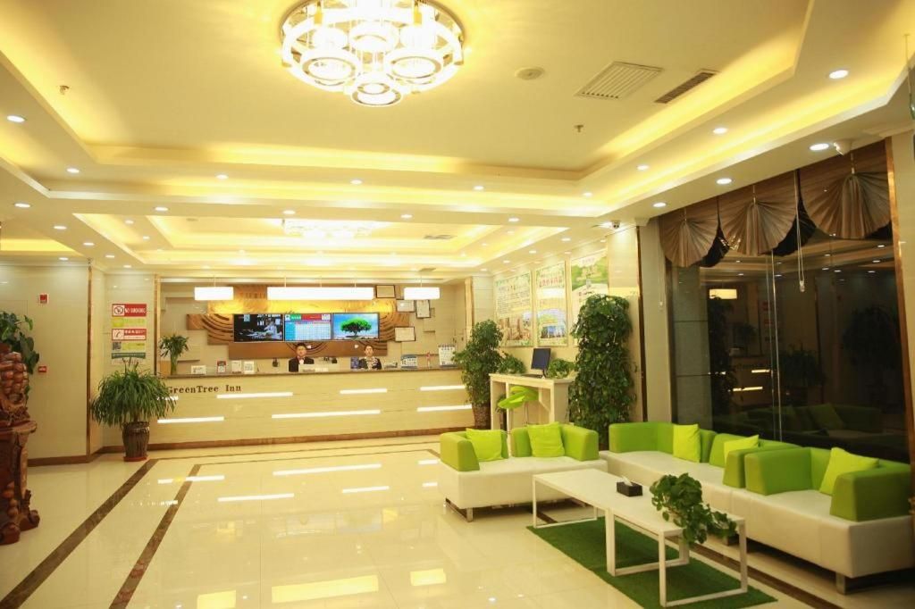 A hotel lobby with a reception desk, seating area, and a chandelier.