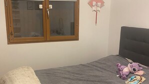 Un dormitorio con una cama, una ventana, un adorno en la pared y un cabecero.
