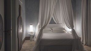 A bedroom with a canopy bed, a bedside table with a lamp, and a wall-mounted clock.