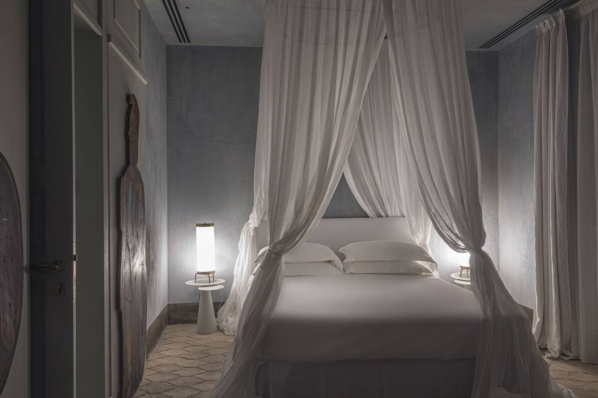 Une chambre à coucher avec un lit à baldaquin, une table de chevet avec une lampe et une horloge murale.