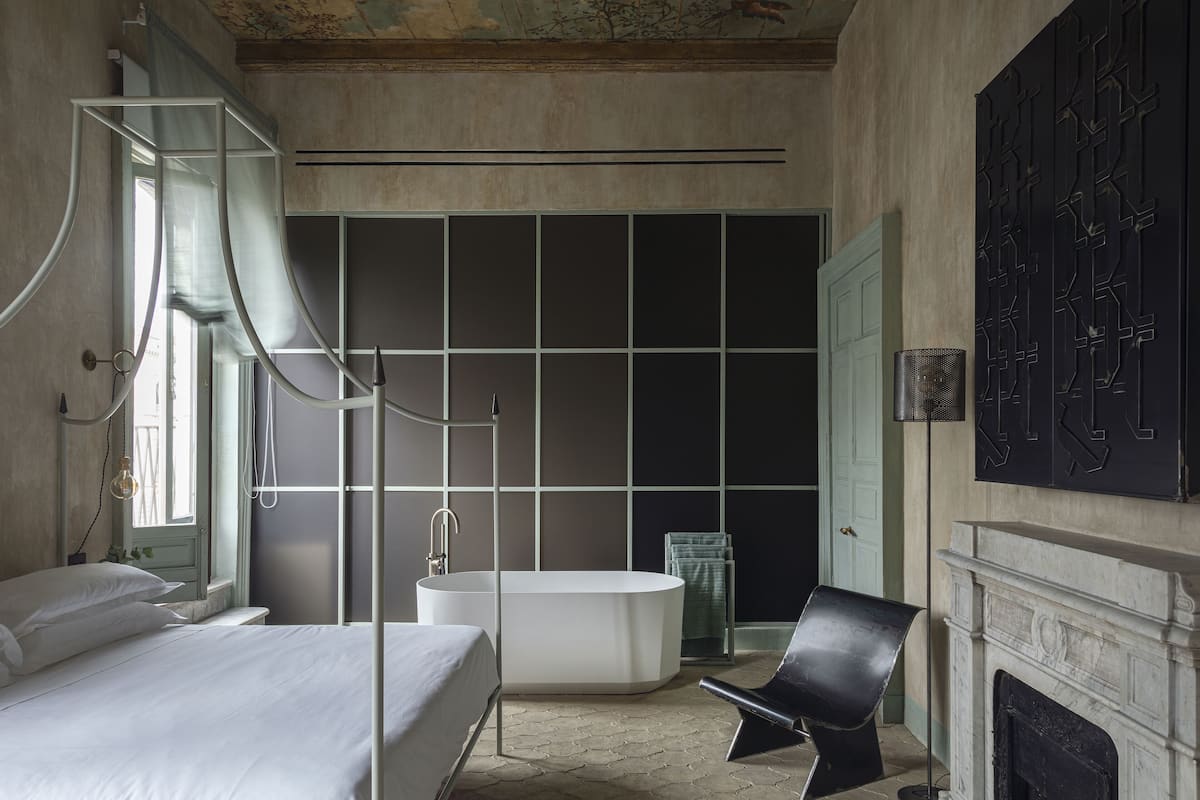 Une salle de bain moderne avec une baignoire sur pieds, un grand miroir et une chaise noire.
