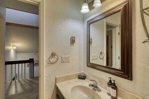 Une salle de bain avec un grand miroir, un lavabo et un porte-serviettes.