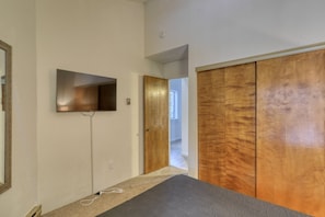 Ein Flur mit einem an der Wand befestigten Flachbildfernseher, einer Tür zu einem anderen Raum und einem Holzschrank.