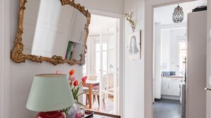 A hallway with a wooden table, a red lamp, and a patterned rug. - Flowers from Paris, by Veeve (Paris)