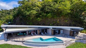 A modern house with a swimming pool, outdoor seating, and a covered patio. - Luxurious Ultramodern Property with Private Suites, Infinity Pool, and Sweeping Ocean and Mountain Views (Las Catalinas)