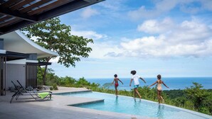 A swimming pool with a view of the ocean, surrounded by greenery and modern architecture. - Luxurious Ultramodern Property with Private Suites, Infinity Pool, and Sweeping Ocean and Mountain Views (Las Catalinas)