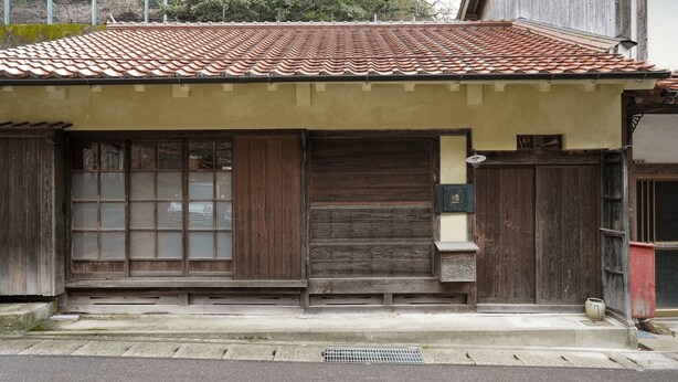 Ein traditionelles japanisches Gebäude mit einem Ziegeldach, Holztüren und einem kleinen Eingangsbereich.