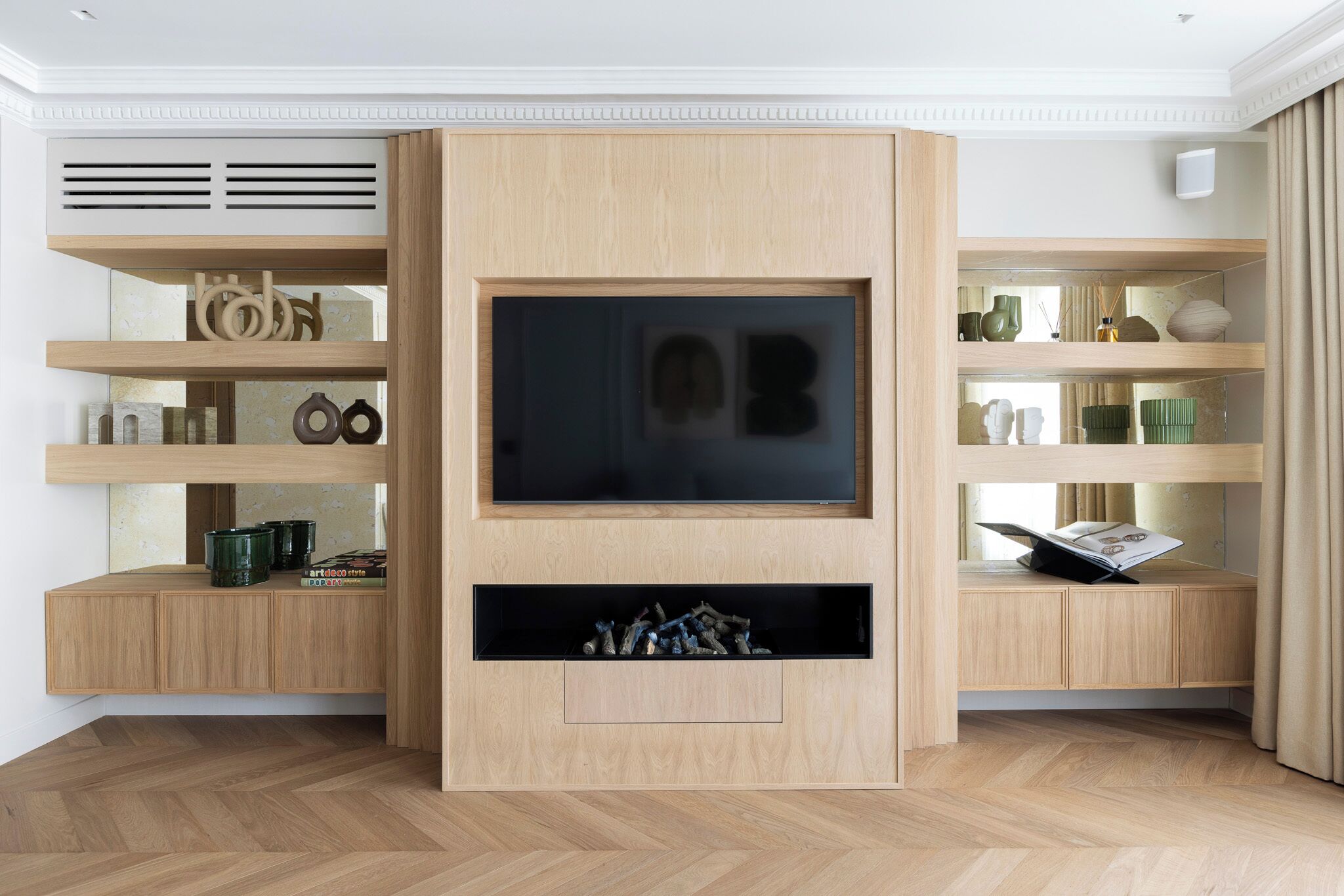 Una sala de estar moderna con televisor empotrado, estanterías de madera y chimenea.