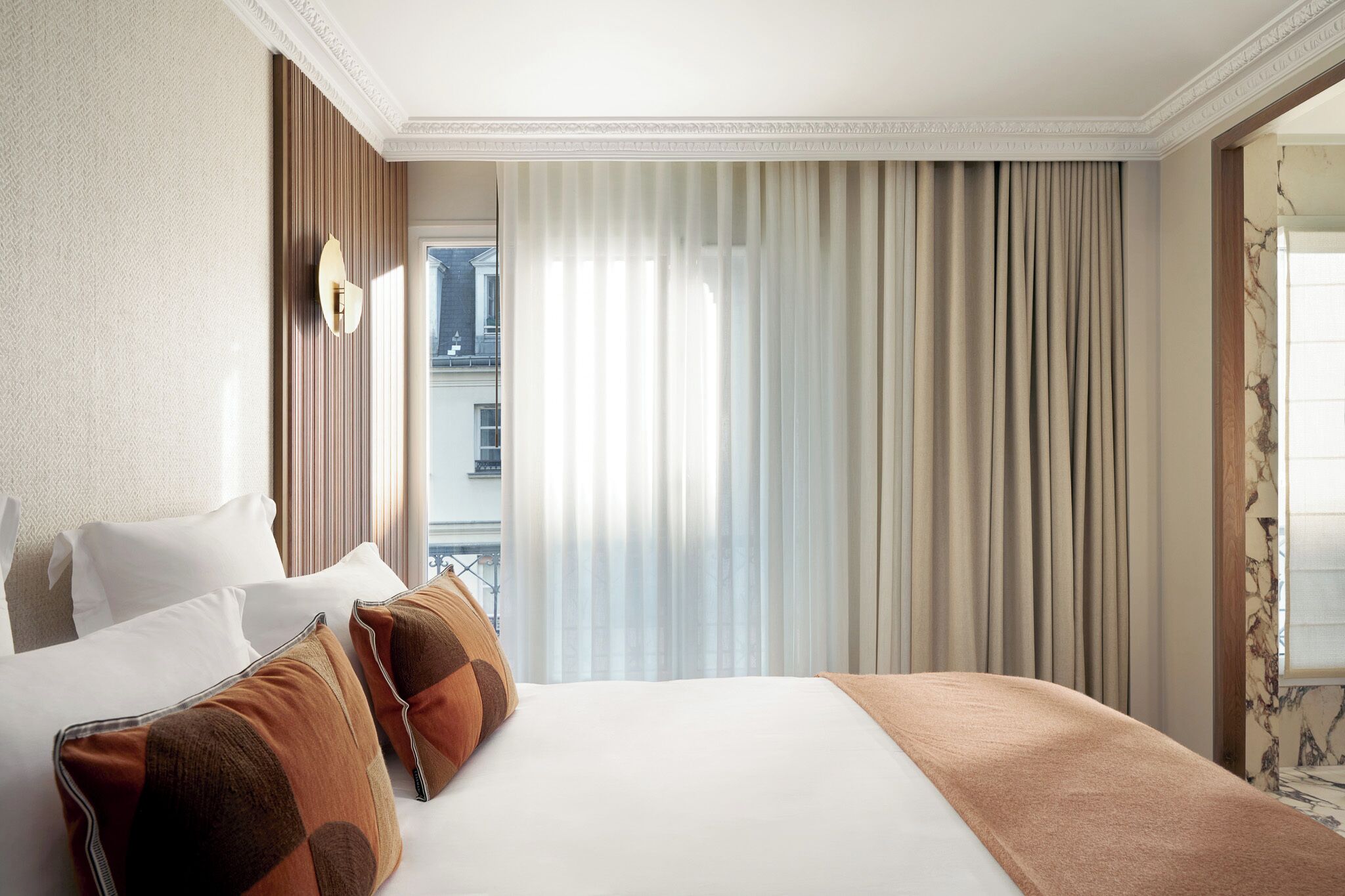 A hotel room with a large bed, a view of the city, and a window with curtains.