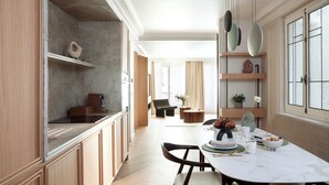 Eine moderne Küche mit Marmorarbeitsplatte, Holzschränken und einem Essbereich mit weißem Tisch und Stühlen.