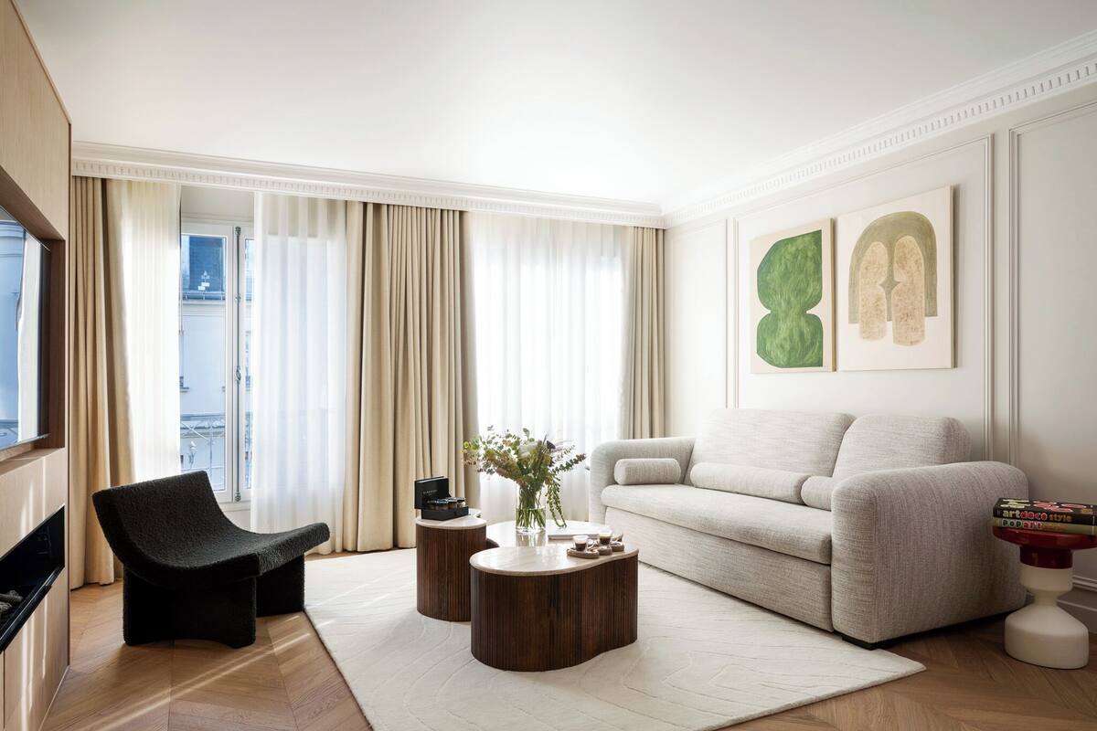 Ein modernes Wohnzimmer mit einer Couch, einem schwarzen Sessel, zwei Holztischen und einem Couchtisch.