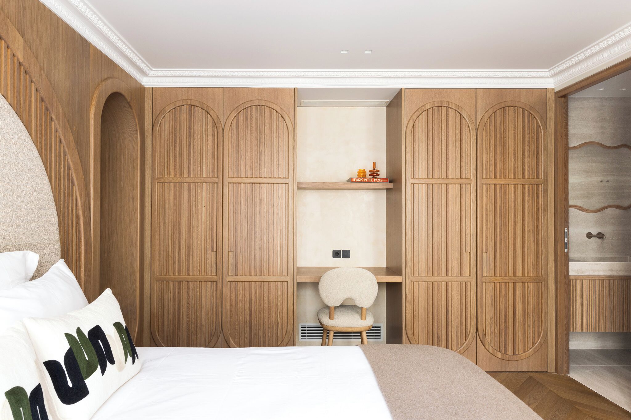 Quarto com cama grande, guarda-roupa de madeira e pequena escrivaninha com cadeira.