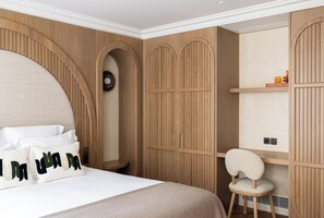 Une chambre avec un grand lit, une armoire en bois et une petite chaise.