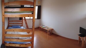 Une chambre avec un lit superposé, une petite table et un meuble pour la télévision.
