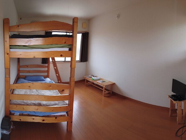Habitación con literas, una pequeña mesa y un mueble para televisión.