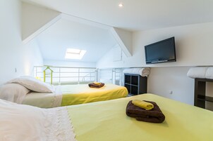 Una habitación de hotel con dos camas, un televisor montado en la pared y un tragaluz.