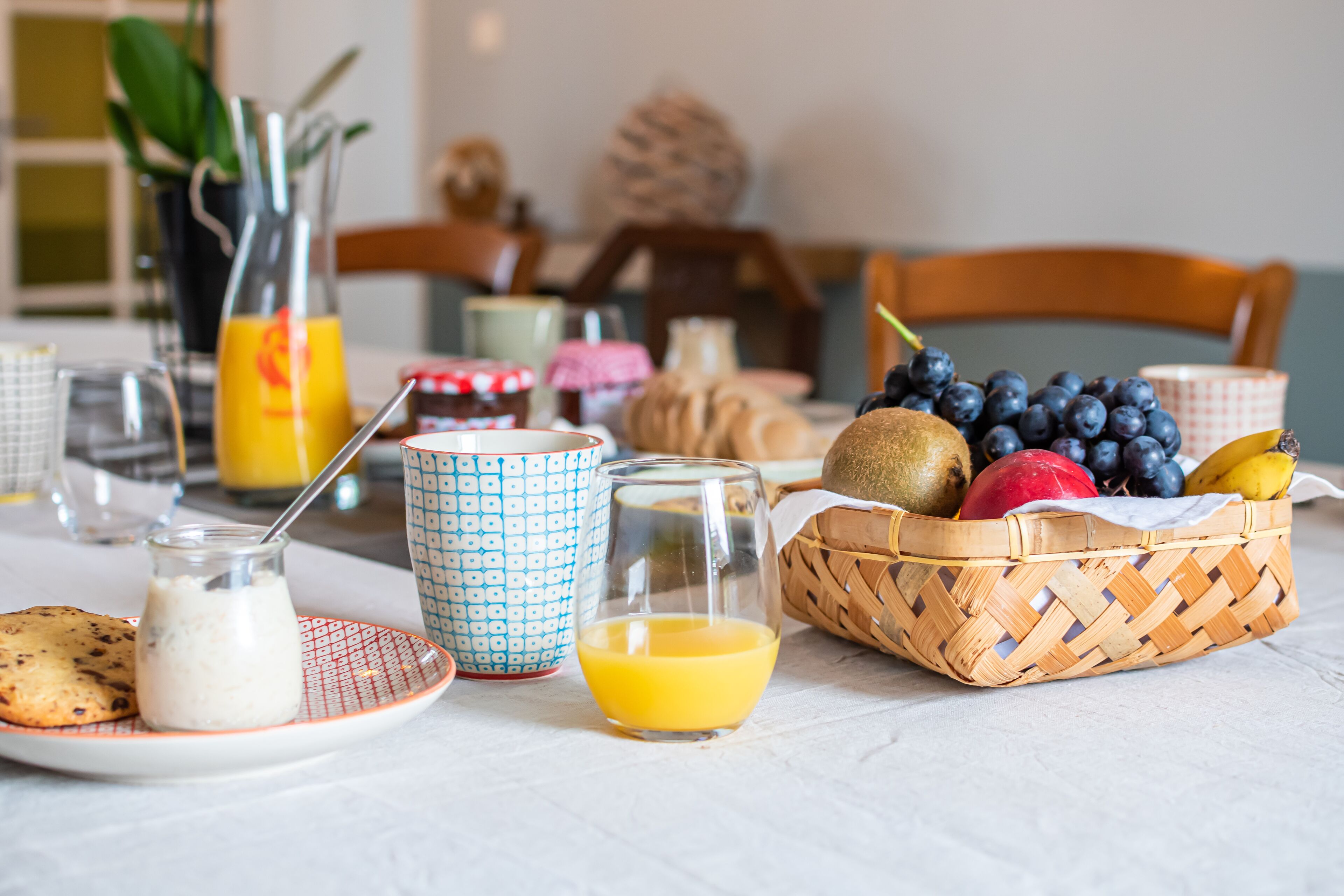 Ein Frühstücksbuffet mit Obstkorb, Orangensaft und einem Teller mit einem Muffin und einer Sahnecreme.