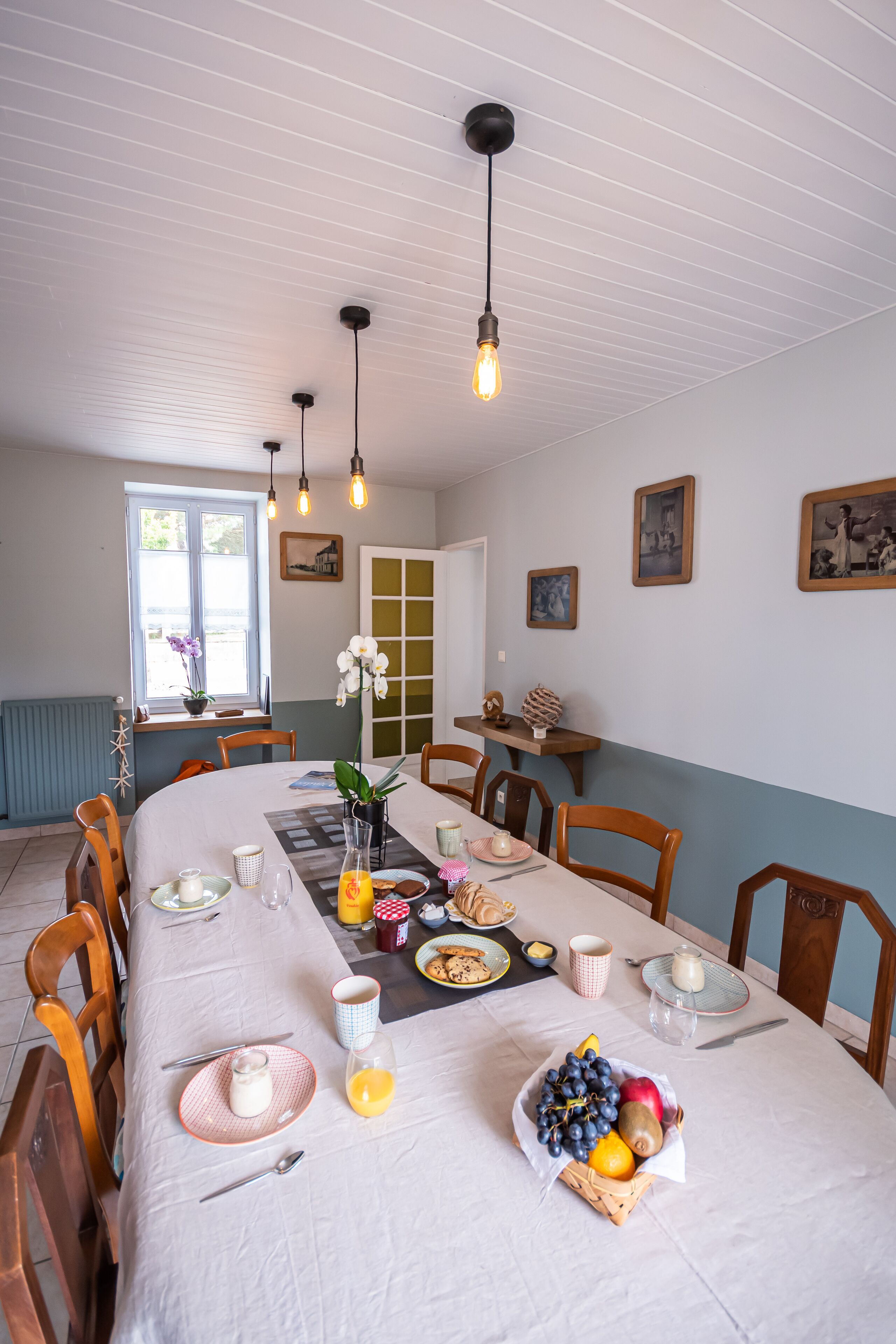 Comedor con una larga mesa preparada para una comida, que incluye diversos platos, frutas y bebidas.
