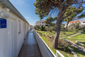 A corridor with a sign indicating a studio apartment, leading to a landscaped garden area with trees and a pathway. - Studio Apartman Blue View (Dubrovnik)
