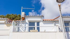 A white building with a tiled roof, a satellite dish, and a small balcony with a table and chairs. - Studio Apartman Blue View (Dubrovnik)