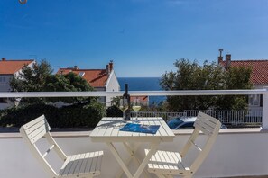 En balkon med bord og stole med udsigt over kysten.