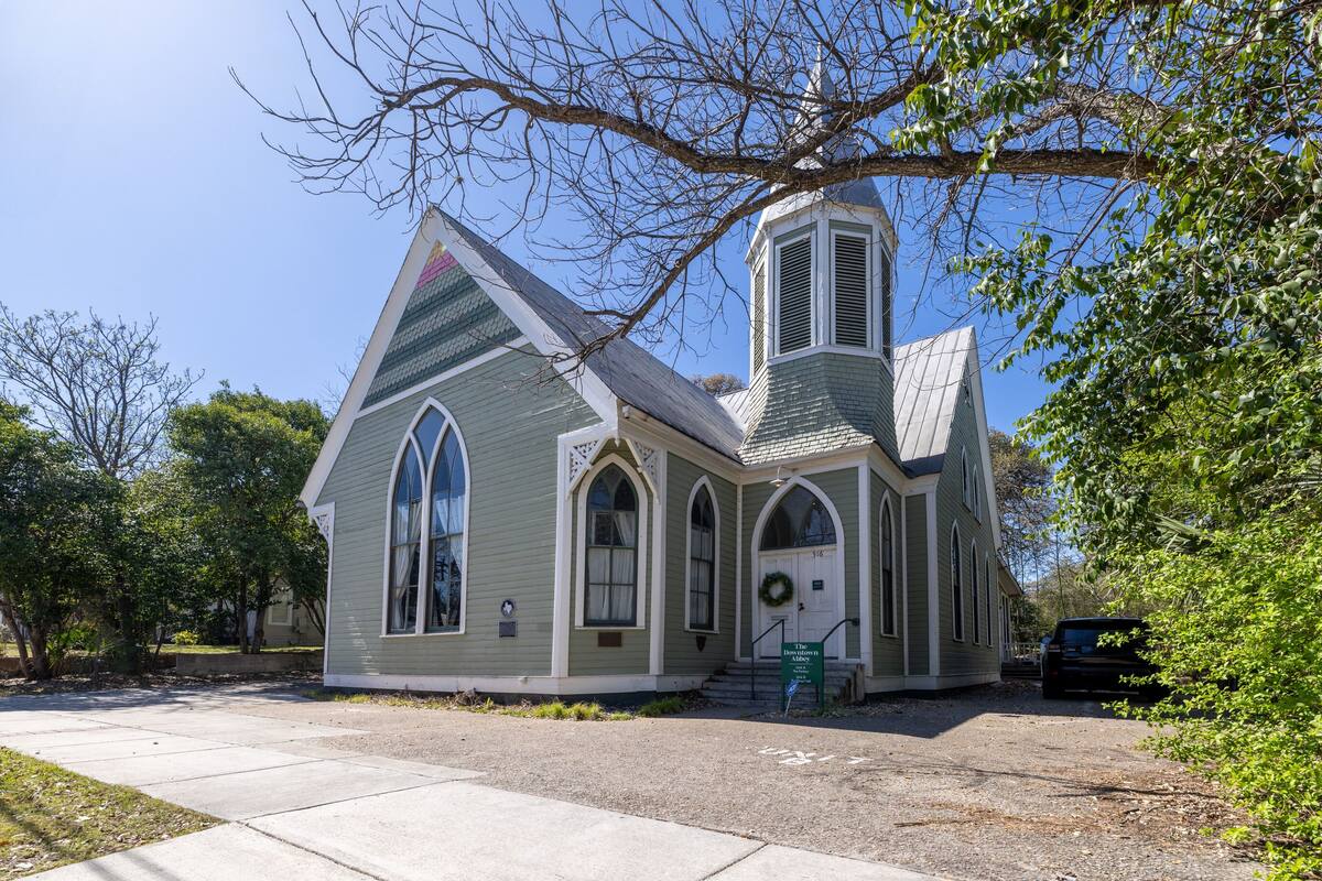 A small church with a steeple and arched windows.