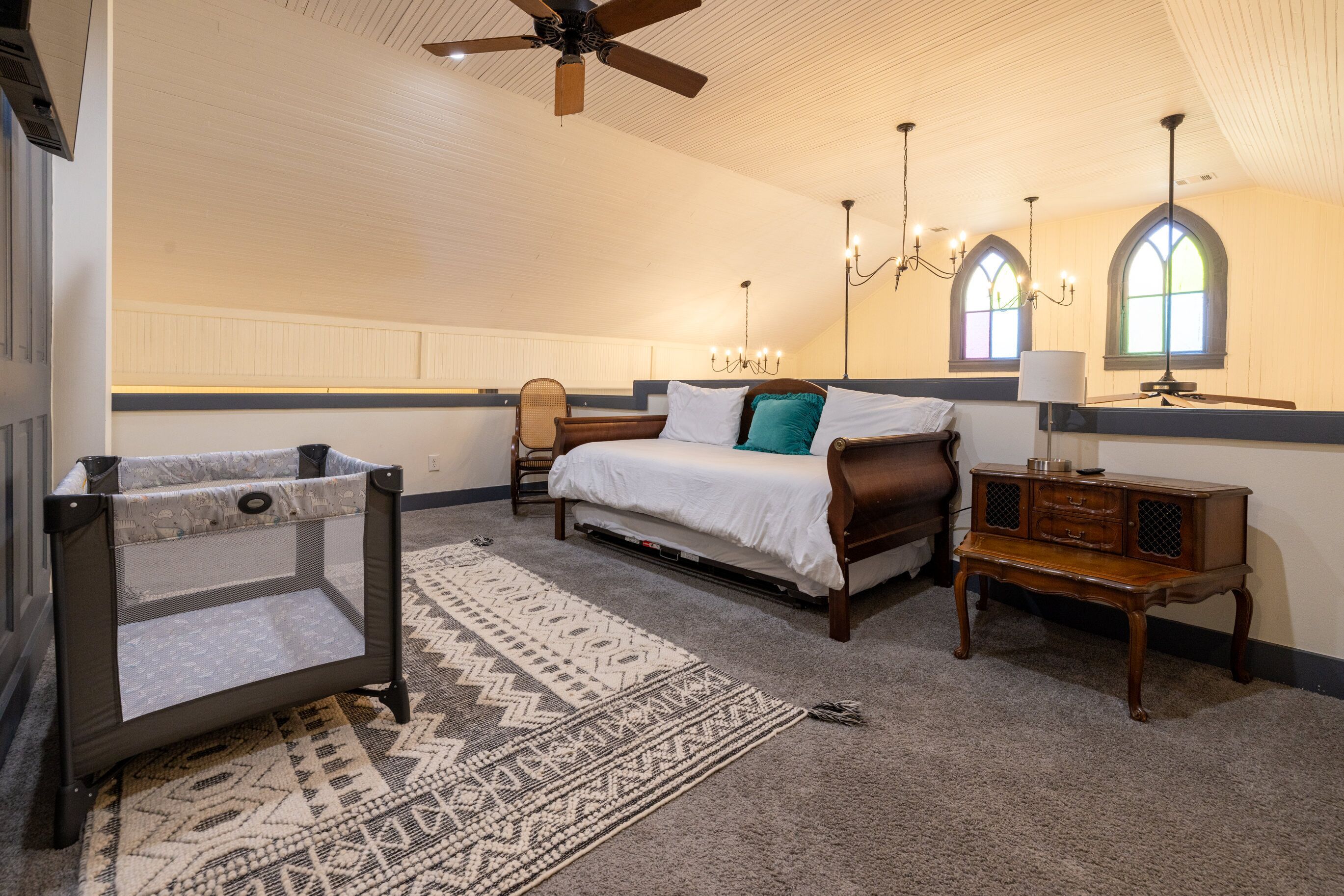 Une chambre spacieuse avec un grand lit, un ventilateur de plafond, une table de chevet et une fenêtre donnant sur un beau paysage.