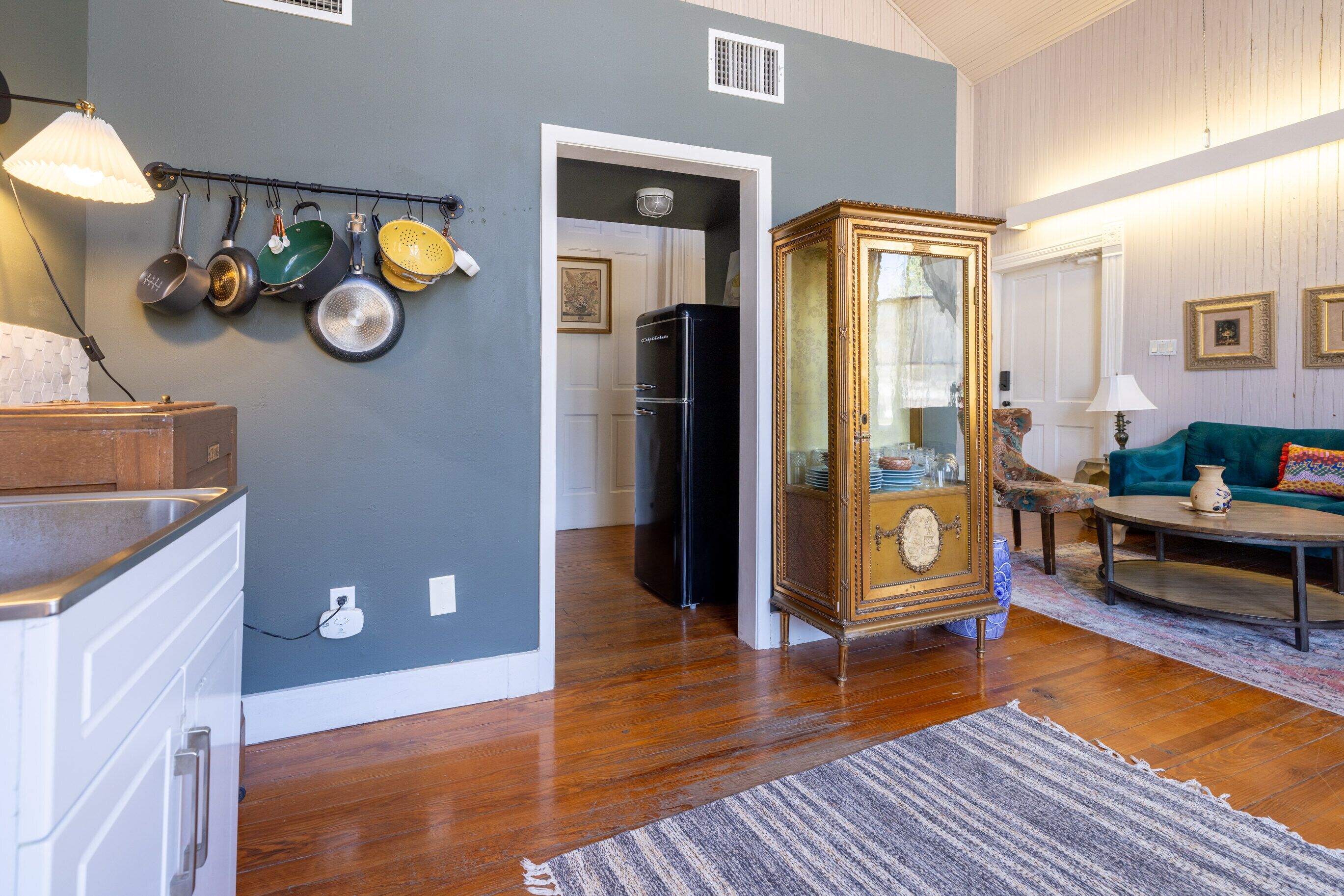 A kitchen with wooden cabinets, a hanging pot rack, and a refrigerator.